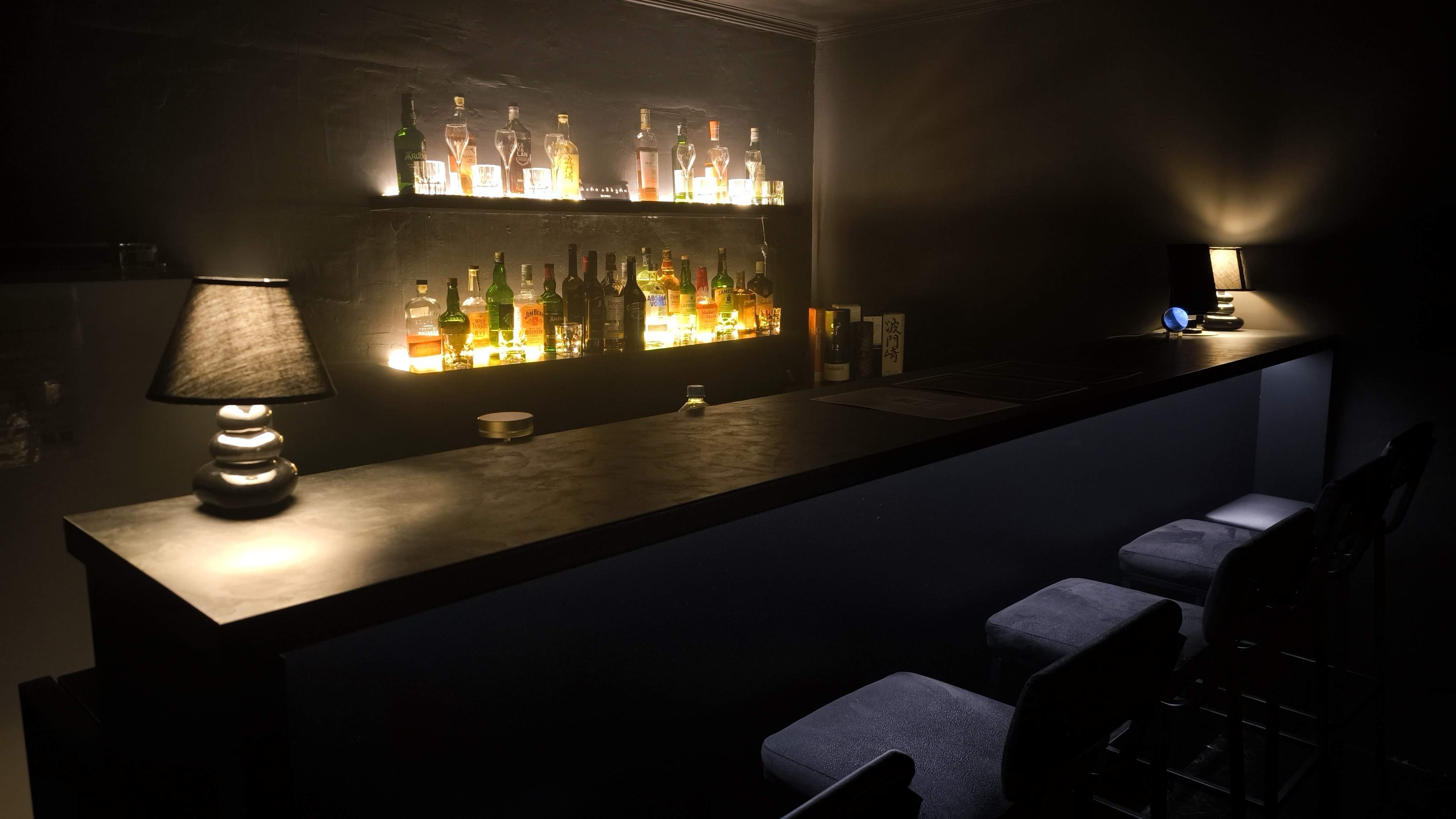 Candlelit natural whisky bar interior in Tbilisi with a black wooden counter